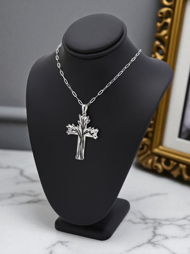 Silver cross necklace on a black bust with a gold frame in the background